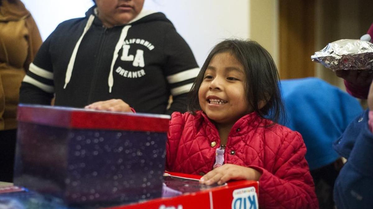 A young girl smiles as she receives gifts following the Merced County Rescue Mission’s Christmas Eve meal at the American Legion Hall on Saturday.