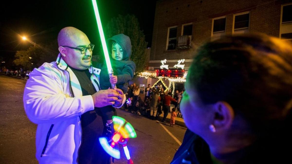 Oscar Lainez, 29, of Newman, left, holds 11-month-old son Mathias, as they look at lighted toys during the Gustine Chamber of Commerce 2016 Downtown Christmas Parade in Gustine, Calif., on Saturday, Nov. 26, 2016.