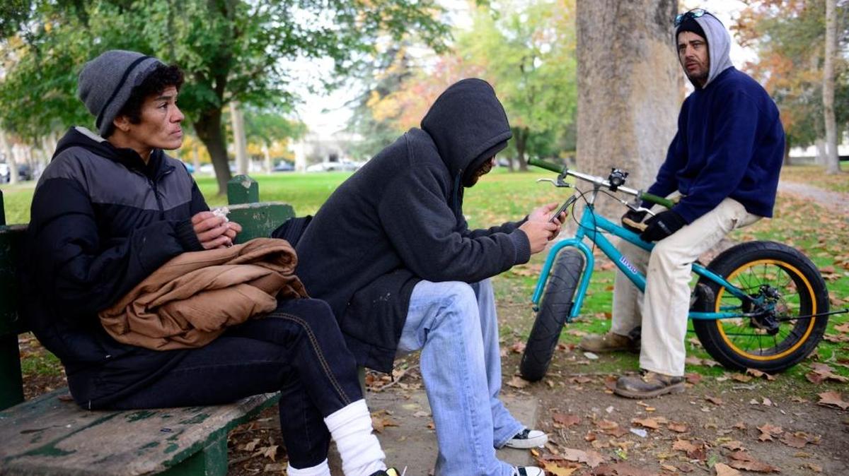 Latasha Parker, 43, left, and Michael Duree, 40, flank a homeless man who declined to be identified as they talk in Courthouse Park about the efforts they go to while trying to stay warm during cold nights living on the streets of Merced on Wednesday, Dec. 2, 2015. They said they wear layers of clothes, pile on blankets when they can and even snuggle up next to pets to stay warm, among other practices.