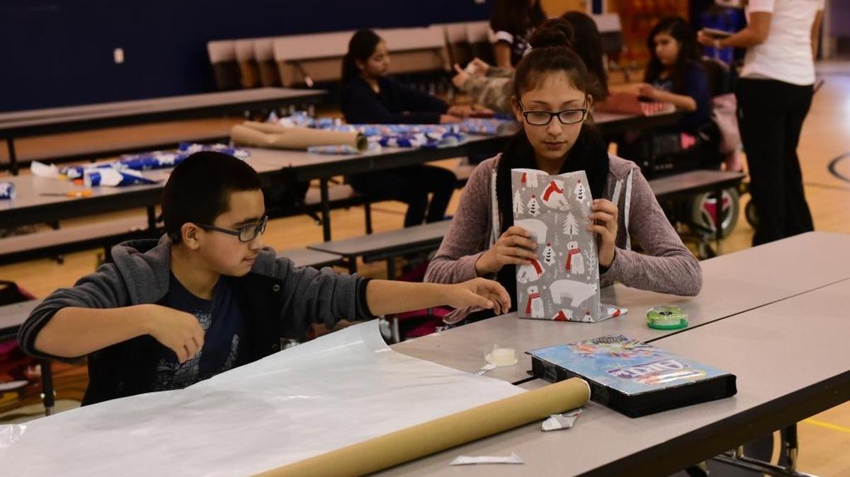 Jorge Guardado, 13, and Roxanna Gonzalez, 14, wrap presents on Tuesday in the cafeteria at Cesar E. Chavez Middle School in Planada. The donated gifts will be given to students at Planada Elementary School.