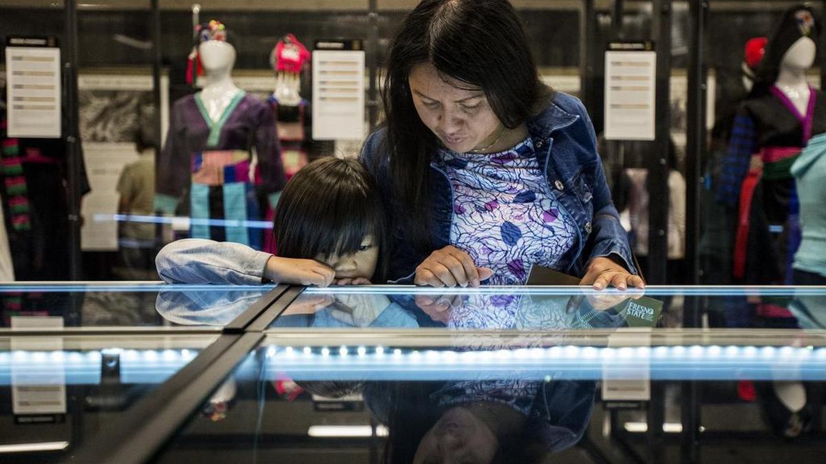 Merced resident Senda Chang, 35, looks at currency with son Micah Thao, 6, during the opening of the Hmongstory 40 exhibit Saturday, May 7, 2016, at the Merced County Fairgrounds in Merced. The exhibit features documentaries, hands-on displays, stories and photos of Hmong history and their first 40 years in the United States.