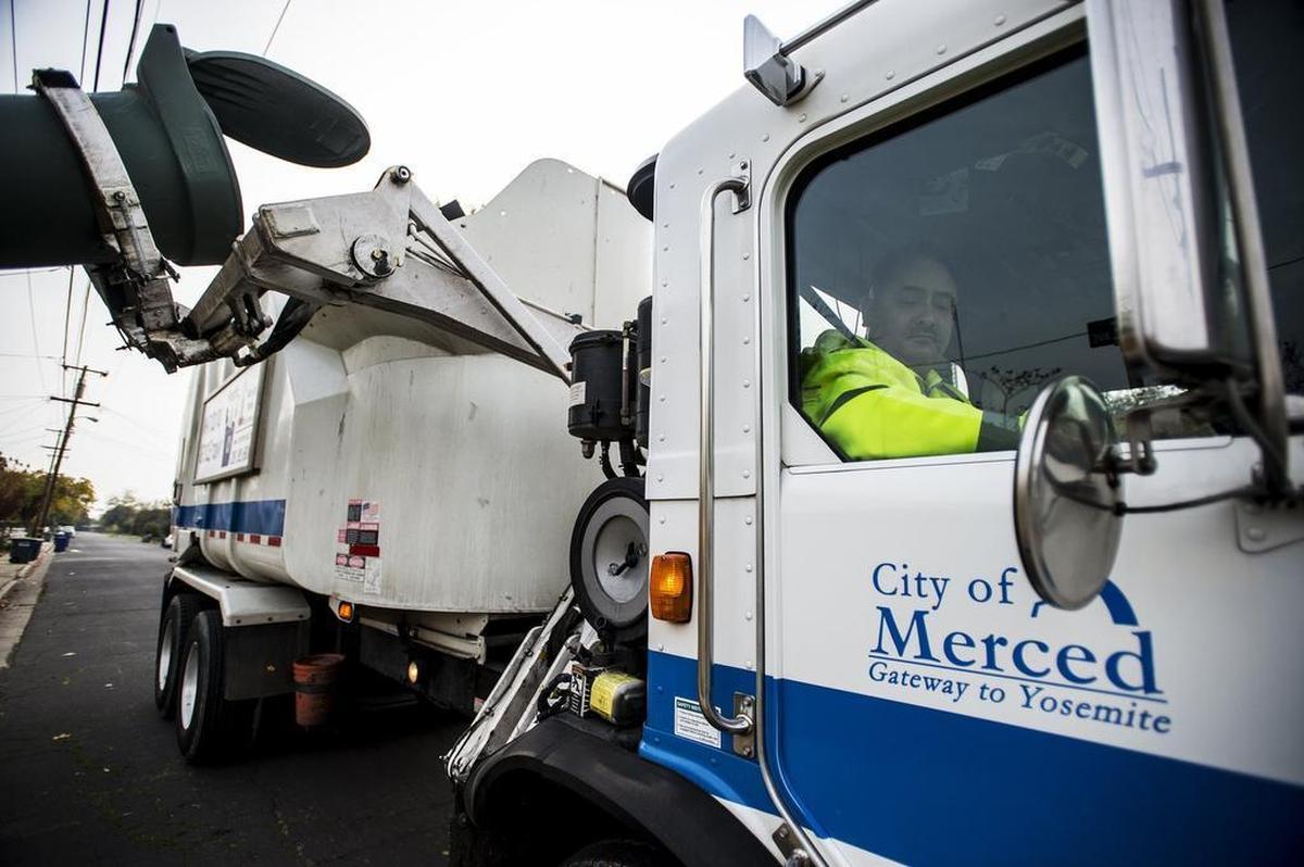 David Soto watches the mechanical arm in the side mirror of his recycling truck while collecting green waste this month in Merced.