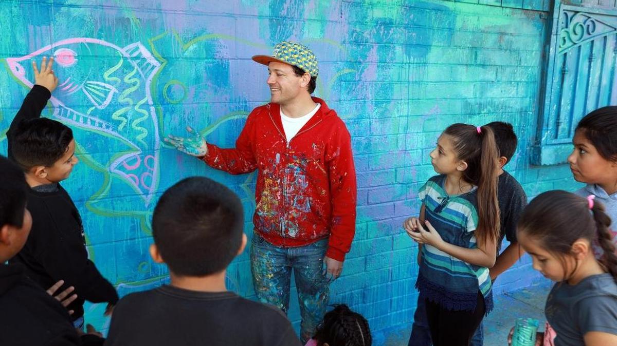Renowned mural artist Joel Bergner speaks with Planada students at Glen Davis Ballpark near Planada Elementary School.