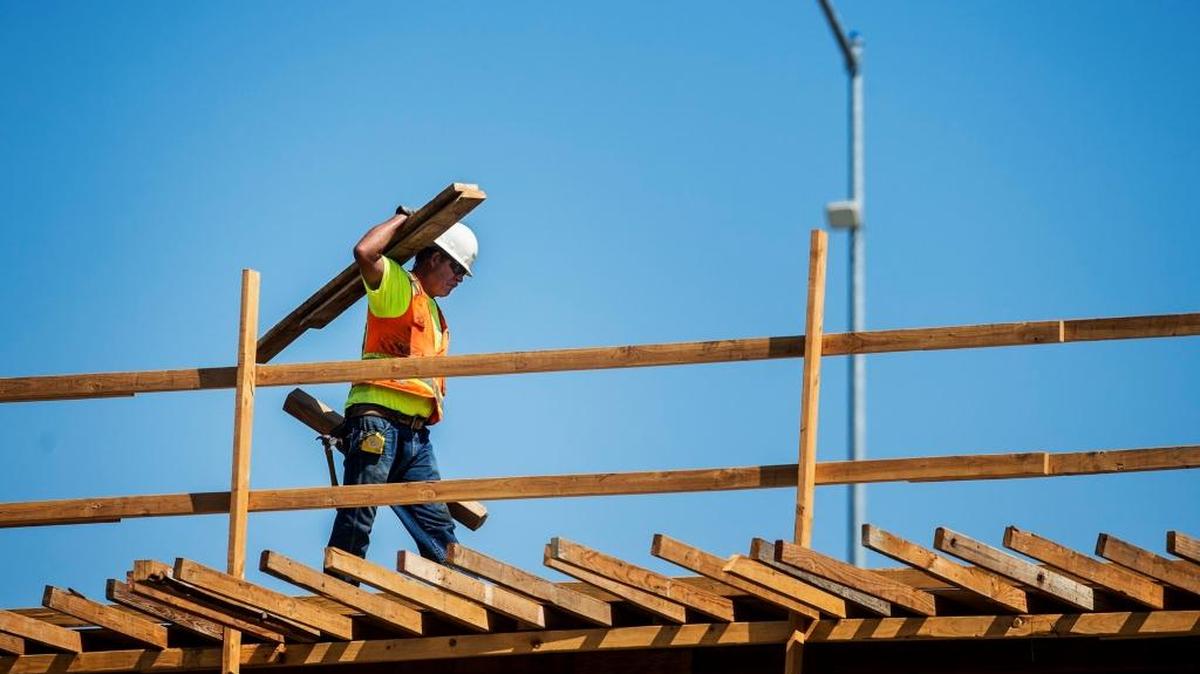 A worker carries lumber during California Department of Transportation work on Highway 99, as seen from 16th Street in Merced, Calif., in July 2015. The job market has improved in the past year, with California employers adding 420,800 payroll jobs since March 2015.