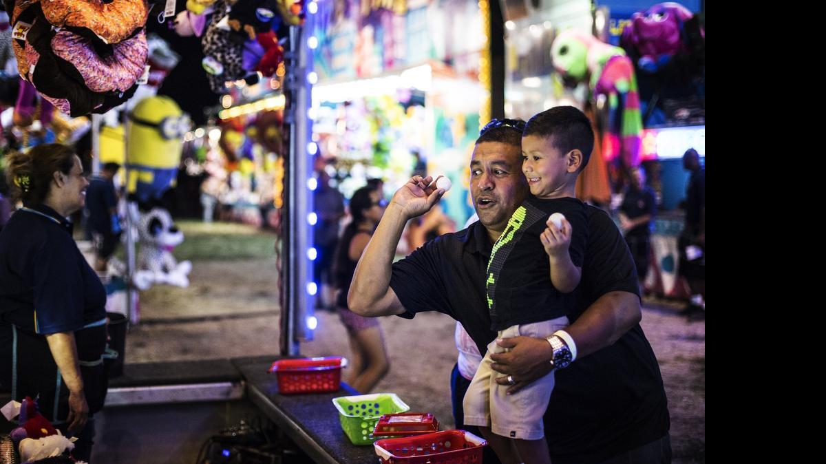 
Fabian Aguilar of Merced prepares to throw a ping-pong ball with son Azariah, 3, during a carnival game at the Merced County Fair in Merced on June 11.
