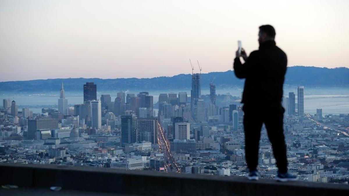 A visitor takes photos of the city skyline at sunrise Thursday in San Francisco. Thursday’s clear skies were expected to cloud over on Friday with a storm system forecast to bring wind and rain to Merced County, and snow to the Sierra mountains.