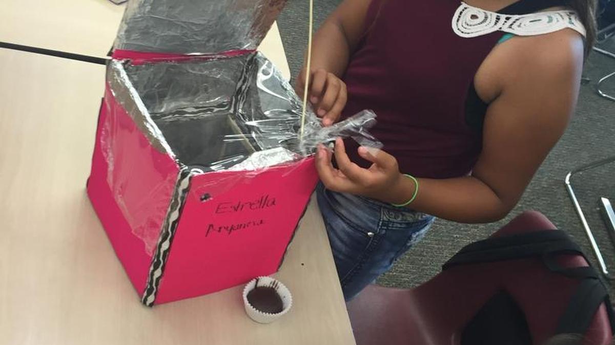 Livingston Middle School summer student Aryanna Romo 13, top, takes out a cupcake from the solar oven she made with Estrella Estrada, 13, on June 21, 2016 in their classroom.