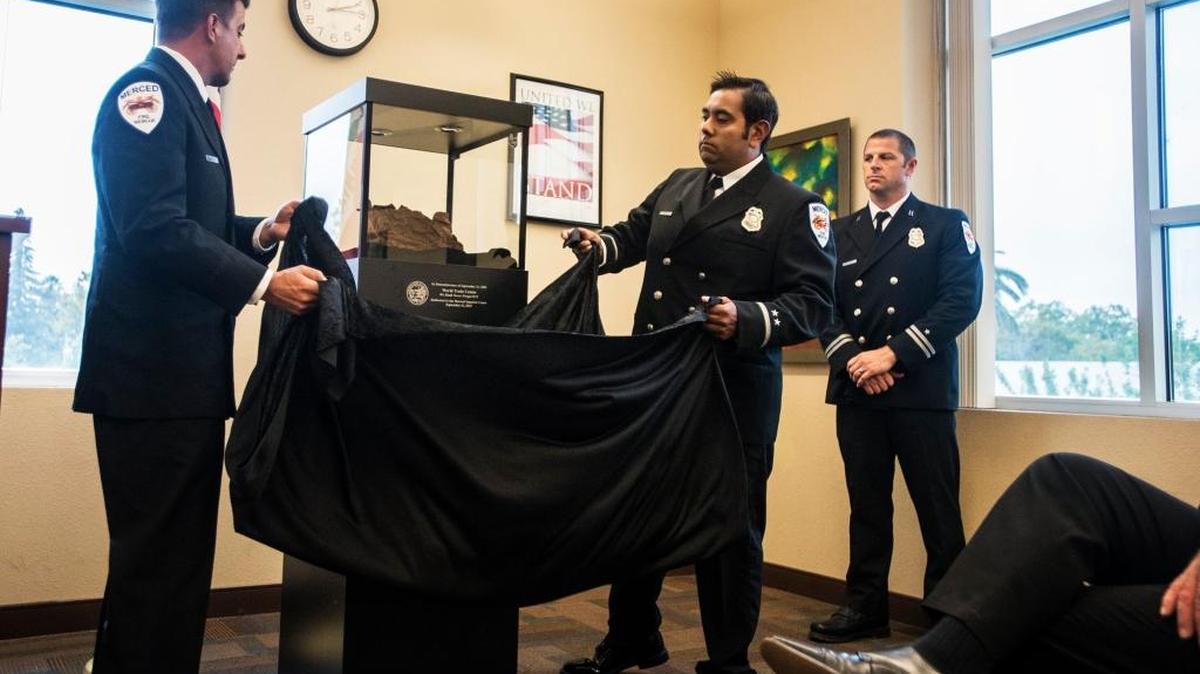 From left, Merced firefighters Craig Mariucci, Engineer Rich Ramirez and Capt. Chad Englert unveil a World Trade Center artifact during a 9/11 memorial ceremony last year in Merced Superior Court.