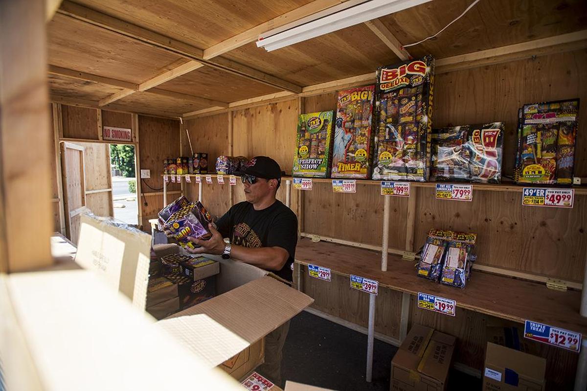 Golden Valley High School band director Michael Vasquez, 37, of Merced, places fireworks on shelves for sale at the TNT Fireworks stand located at the intersection of G Street and East 18th Street in Merced, Calif., Tuesday, June 28, 2016. Proceeds from the sales go to the Golden Valley High School marching band.