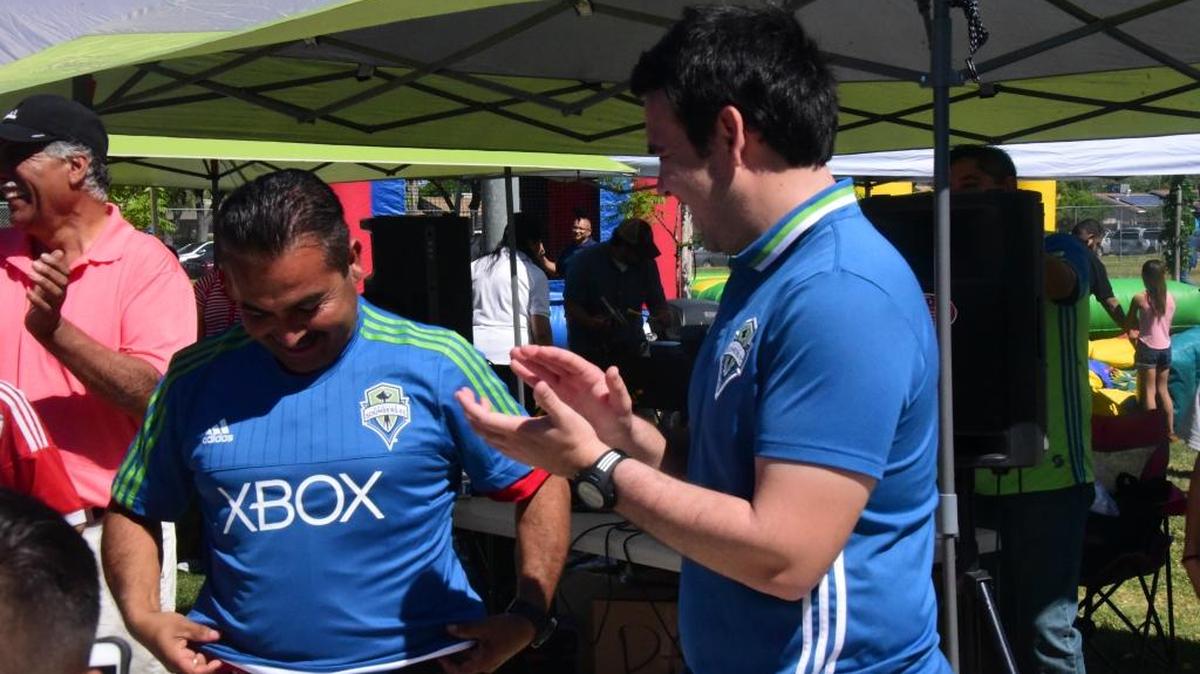 Merced Soccer Academy president, Fernando Aguilera, is putting on his new Merced Sounders jersey on Sunday, April 30, 2017 during a ceremony at McNamara Park in Merced. Henry Brauner (right), coach and scout for the MLS team Seattle Sounders, and Aguilera finalized the partnership between the Academy and the Sounders.