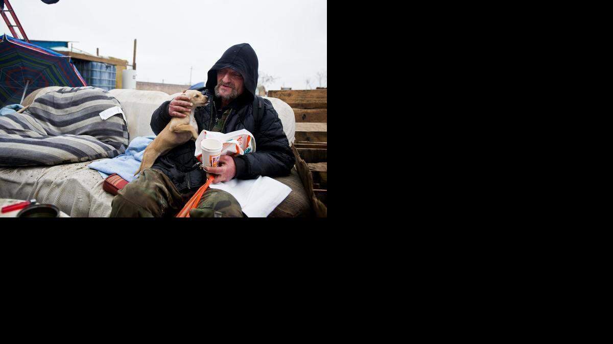 
Brent Shirley, 52, plays with a dog inside a homeless encampment near the Bradley Overpass and Highway 140 at Kelly Avenue in Merced in January. Shirley had been at the encampment for the previous six months. The encampment was cleared in January. 

