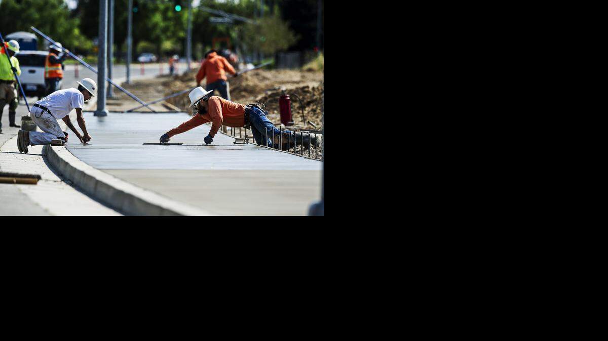 
Philbert Azevedo of Modesto, left, and Manuel Osuna of Manteca work to finish a section of newly poured concrete sidewalk along R Street north of Yosemite Avenue in Merced on Tuesday. According to Jim Breneman, owner of Breneman Inc., this part of the project is funded through air quality grants and should be finished in one week.
