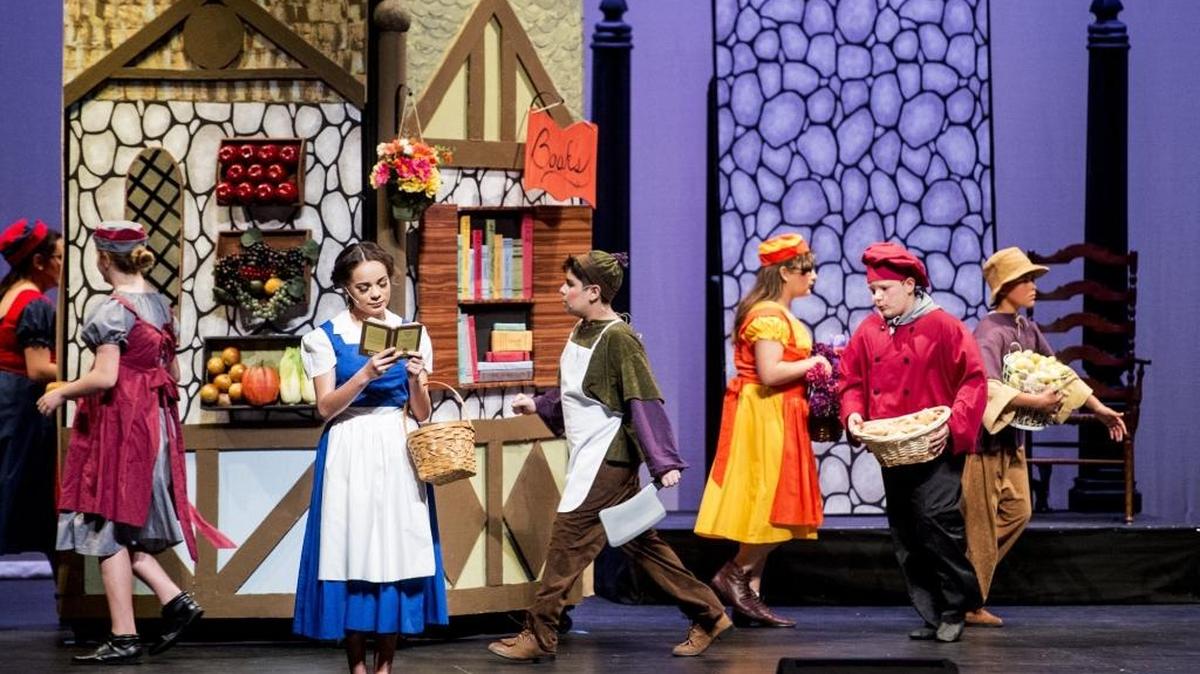 Weaver seventh-grader Emerald Chandler, playing the role of Belle, looks at her book as townsfolk walk past during the Weaver Performing Arts production of "Beauty and the Beast Jr." at the Merced Theatre in Merced, Calif., Tuesday, March 1, 2016. Cast and crew for the production consists of over 60 students from all three schools in the Weaver Union School District.