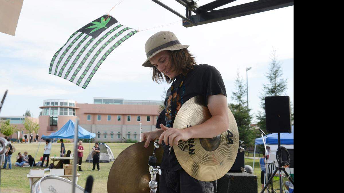 
Greg Hatcher, 18, of Merced sets up his drum set as a flag marked with marijuana leaves flies over his shoulder in a Merced College amphitheater on Monday. Students for Liberty, a college club, put on a marijuana-based event called Legalize Liberty, which featured music and a philosophical debate on the decriminalization of the drug.
