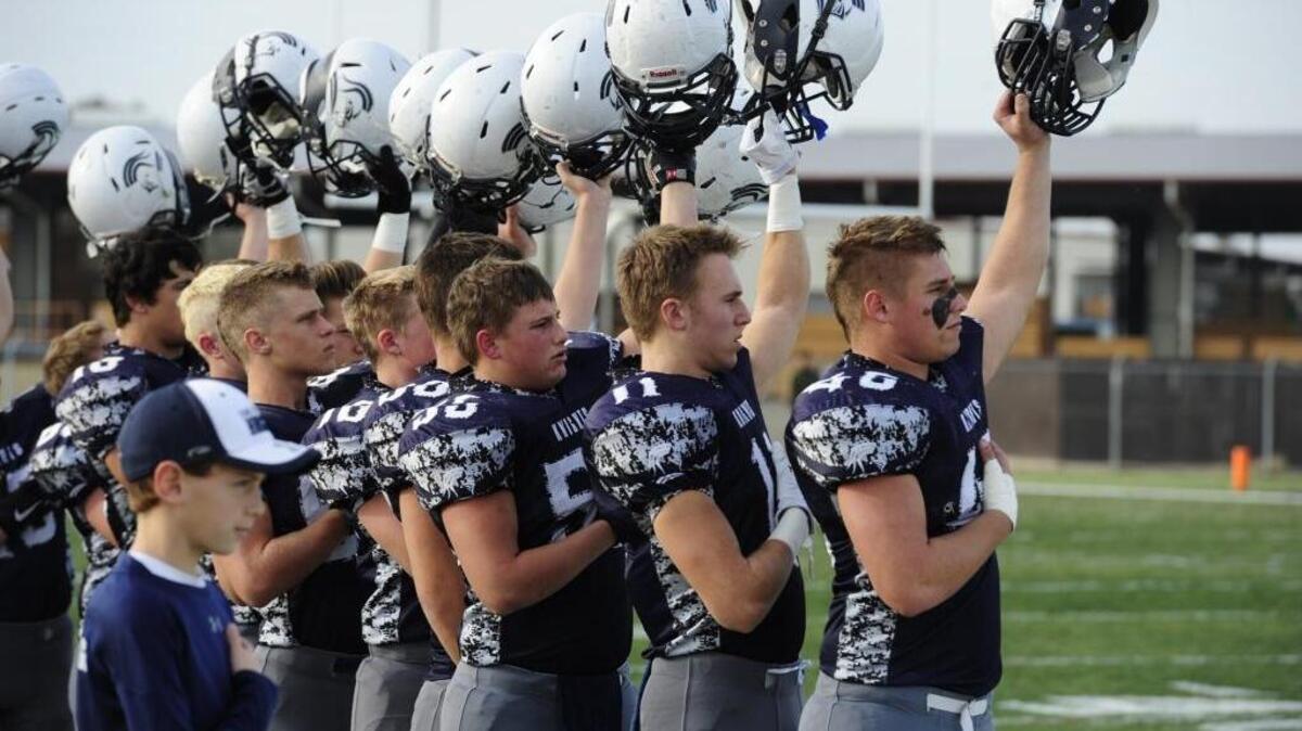 Stone Ridge Christian players raise their helmets together as the national anthem plays during the CIF NorCal Regional play-in game between the Mission High Bears of San Francisco and the Stone Ridge Knights at the Valley Sports Academy in Atwater on Dec. 5.