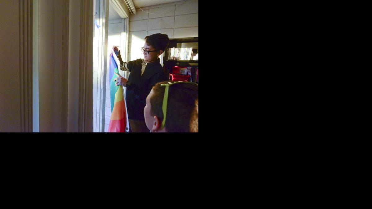 
Marissa Chavez, organizer for the Merced LGBT Center, hangs the rainbow flag inside on Monday after ordered by the building’s owner to take the flag down from the flagpole outside. 
