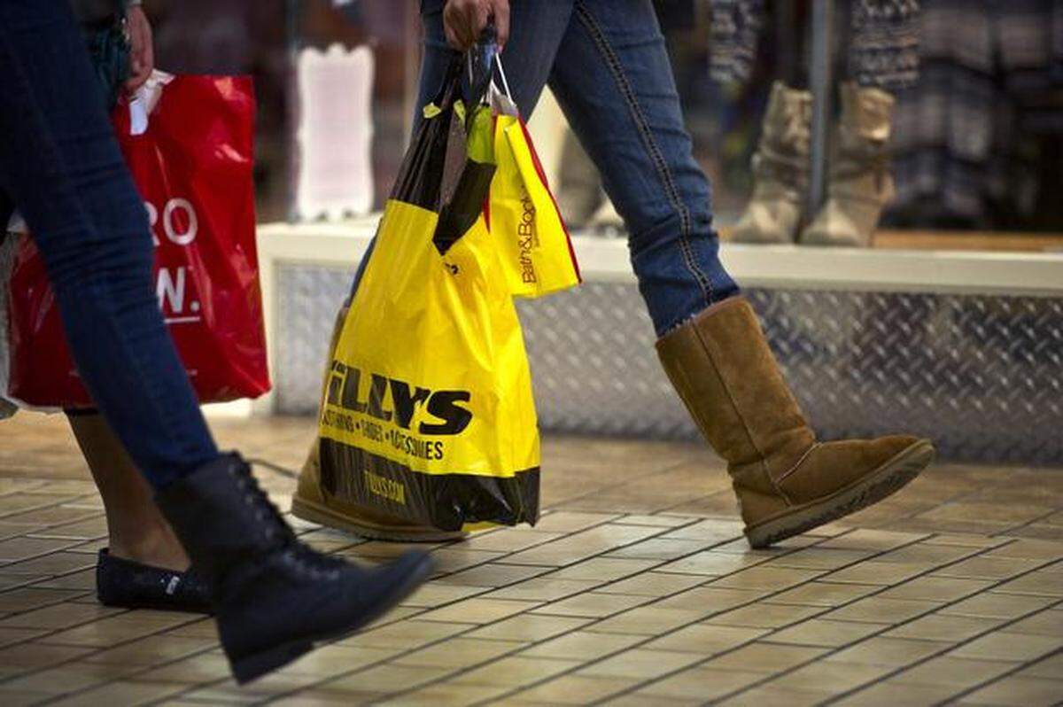 Shoppers carry bags while walking through Merced Mall on Friday. 