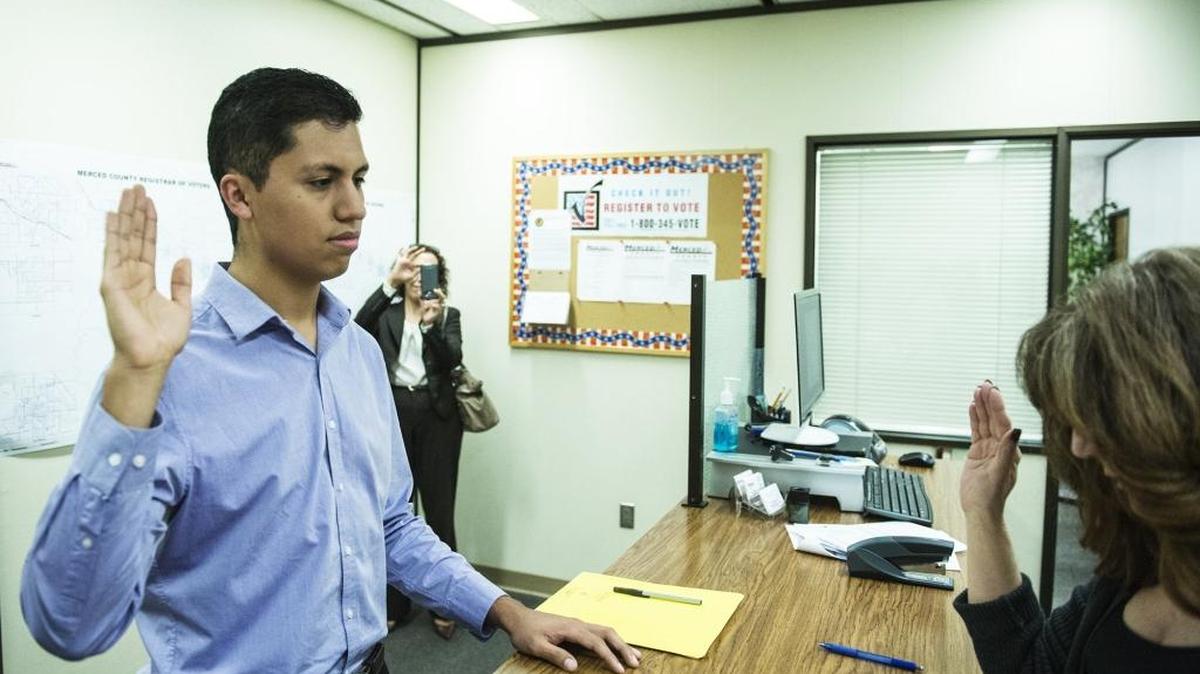 Fidel Cervantes, 23, of Delhi, left, takes an oath from Diana Severson, right, registrar of voters II, as mother Cecilia Cervantes, back, records the moment on her phone at the Merced County Building, 2222 M Street while filing the last of his candidacy papers in Merced, Calif., Wednesday. Cervantes is running for District 4 Supervisor.
