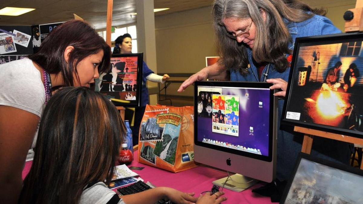 Marti Rose, a graphic arts teacher, looks over the top of a computer while talking to students at Dos Palos High School in 2010. The Dos Palos-Oro Loma Teachers Association has declared an impasse on a new contract with the school district, union leaders announced Wednesday.