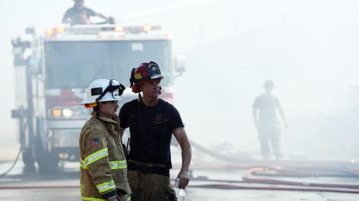 Fire Chief Shawn Henry, left, and another firefighter observe the crew working to extinguish a blaze at the Willow Glen Townhouse Apartments on Yosemite Parkway near Edwards Avenue in Merced, Calif., on Wednesday, Aug. 24, 2016.