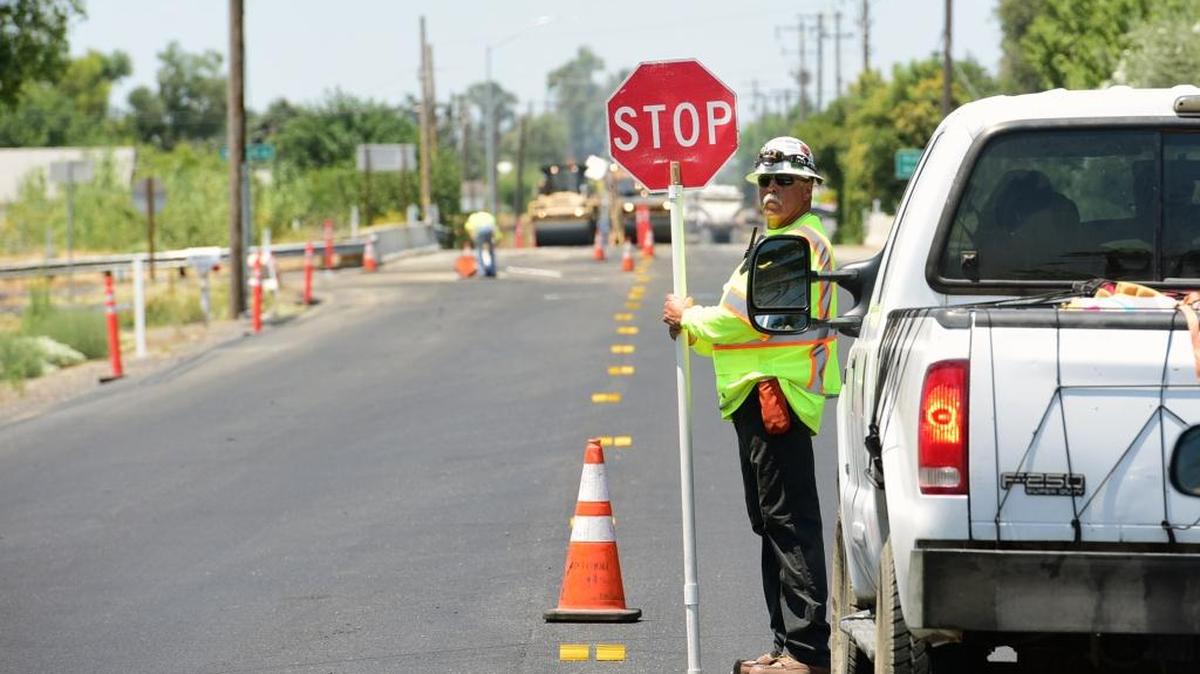 Teichert Construction worker Bryan Reid stops traffic at Highway 140 near Buhach Road on Thursday as resurfacing of the road from Stevinson to Merced continues in Merced. Money from Measure V and State Bill 1 are helping to repair roads in Merced County.