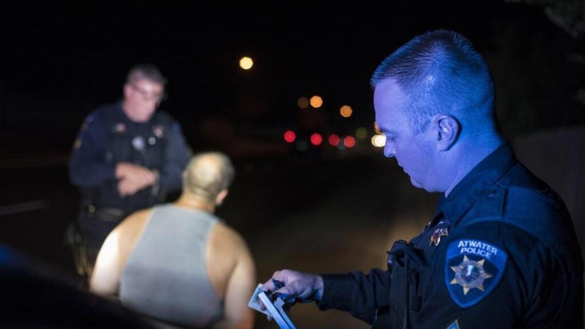 Atwater police Officer Patrick Radke, right, completes paperwork after stopping a man for riding against traffic and citing him for possession of drug paraphernalia in Atwater Calif., Thursday, Oct. 13, 2016. Some community leaders have said that crime in Atwater is on the rise. Statistics do not support that claim.