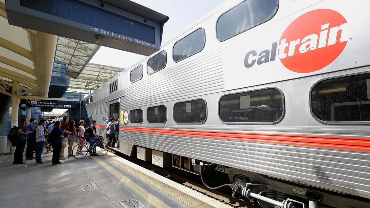 In this July 1, 2013, file photo, commuters board a Caltrain train at the Caltrain and Bay Area Rapid Transit station in Millbrae, Calif. The Trump administration has agreed to fully fund a $650 million federal grant for electrification of a San Francisco Bay Area train system that would also help California's high-speed rail project.