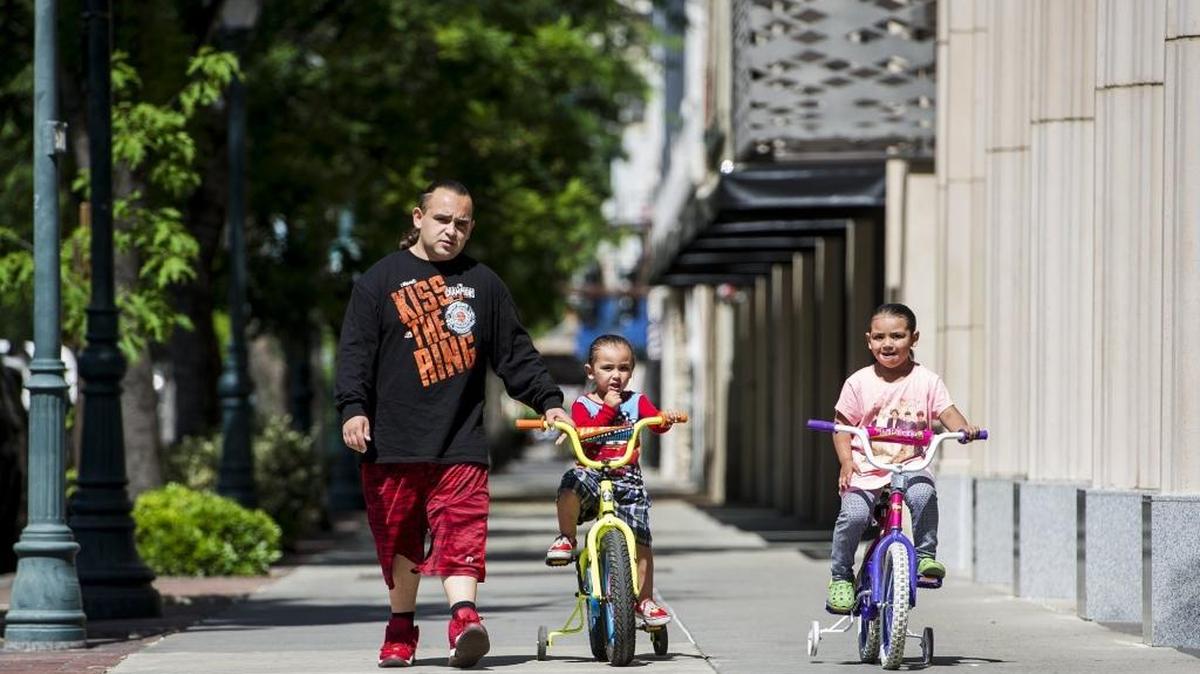 Vincent Cordova, 25, of Merced, walks along West Main Street as his children Vincent Jr., 3, and Isabel, 4, ride their bikes in Merced, Calif., Wednesday, April 20, 2016. May is Bike Month and the first bike event, the Director’s Ride, will take place on April 23.