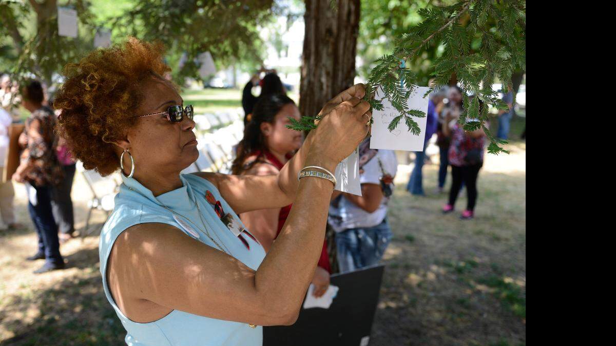 
Marylene Riley of Merced ties a note to a tree dedicated to victims of violent crime in Merced’s Courthouse Park on Thursday during a victims rights ceremony. She tied two notes in memory of her sons Marlis Riley, 27, and Michael Riley, 29, who were killed less than a year apart in 2008 and 2009.
