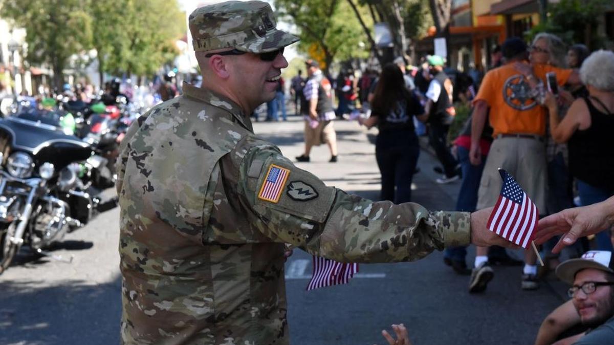 Sgt. 1st Class Zachery Haase, an Army recruiter in town, hands out tiny flags during Merced’s First Responders 9/11 Memorial Parade on Sunday, Sept. 11, 2016.