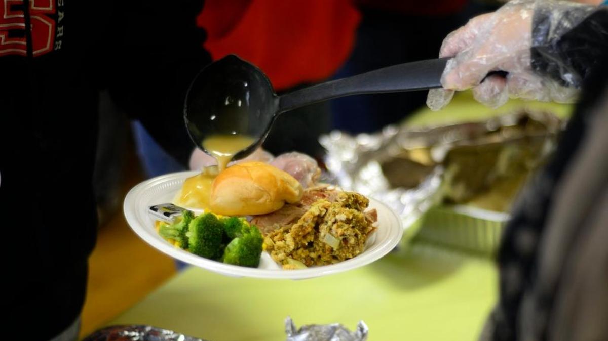 Volunteers prepare a plate of food at the American Legion Hall during the 2015 annual Thanksgiving meal served there. Hundreds of people ate and picked through donated clothes.