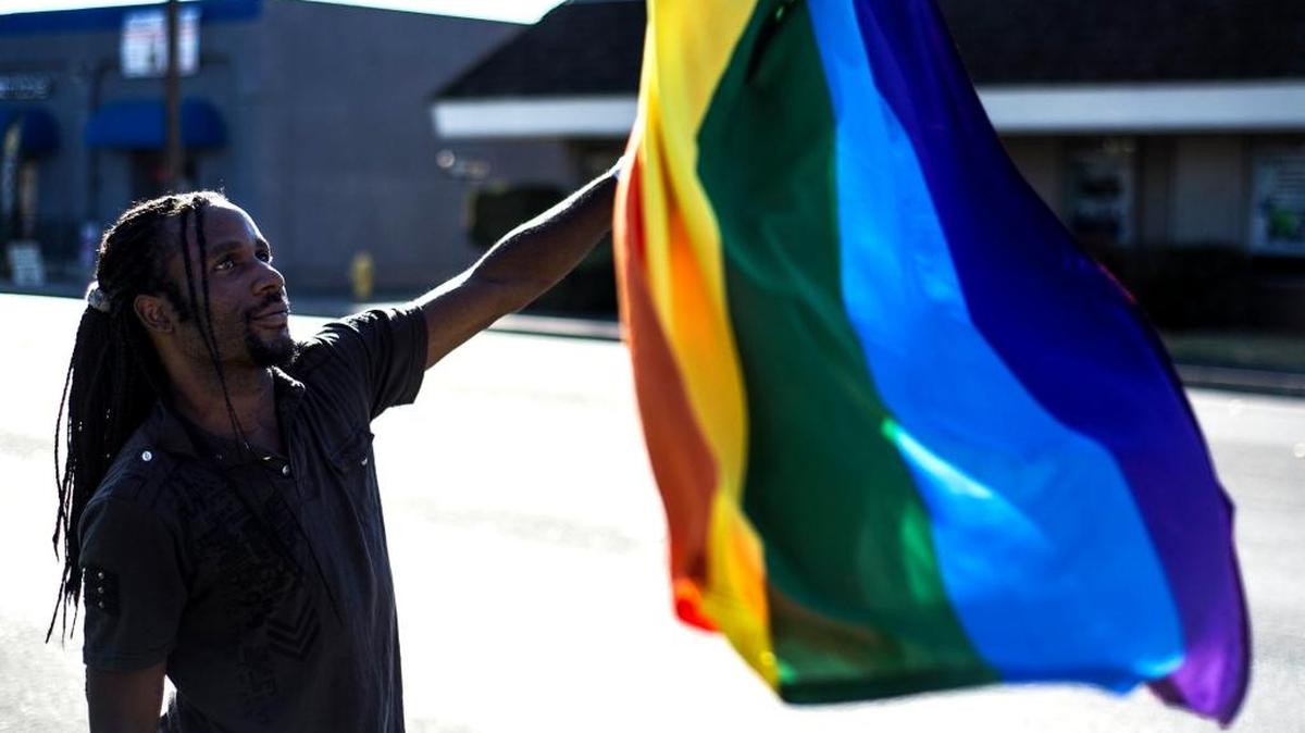 Kevin Hayes, 28, of Merced waves a rainbow flag along G Street during a rainbow ribbon-cutting ceremony to celebrate the reopening of the Merced LGBT Community Center in Merced on Oct. 3, 2015.