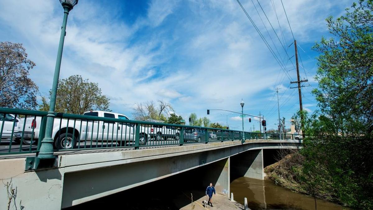 A man walks a dog beneath the G Street overpass in Merced, Calif., on Thursday, March 23, 2017. Contractors will begin work on the M Street and G Street bridges over Bear Creek beginning in April. According to Theron Roschen, an engineer with the city of Merced, work to rehabilitate the bridges will be ongoing through August. The work to be done on each bridge will include rehabilitation to the creek channel and the roadways as well as the structure of the bridges.