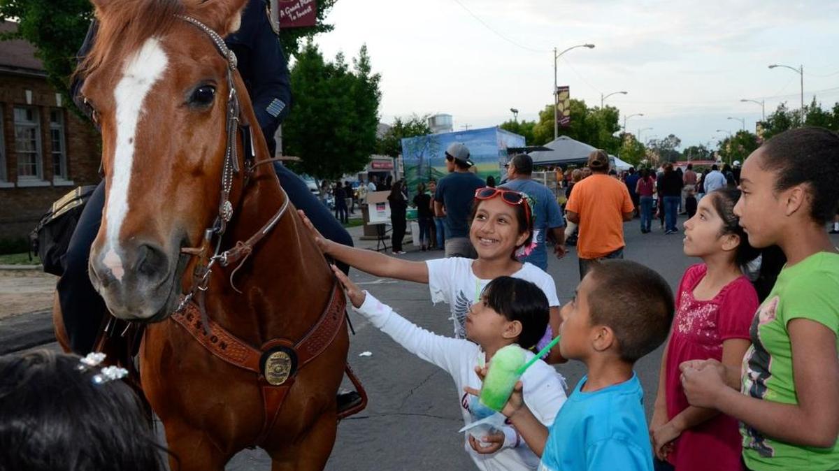 Livingston police Chief Ruben Chavez sits atop rescue horse Mo, as children pet the horse during his debut on the Livingston police squad at the opening of the annual downtown Open Market in 2014.
