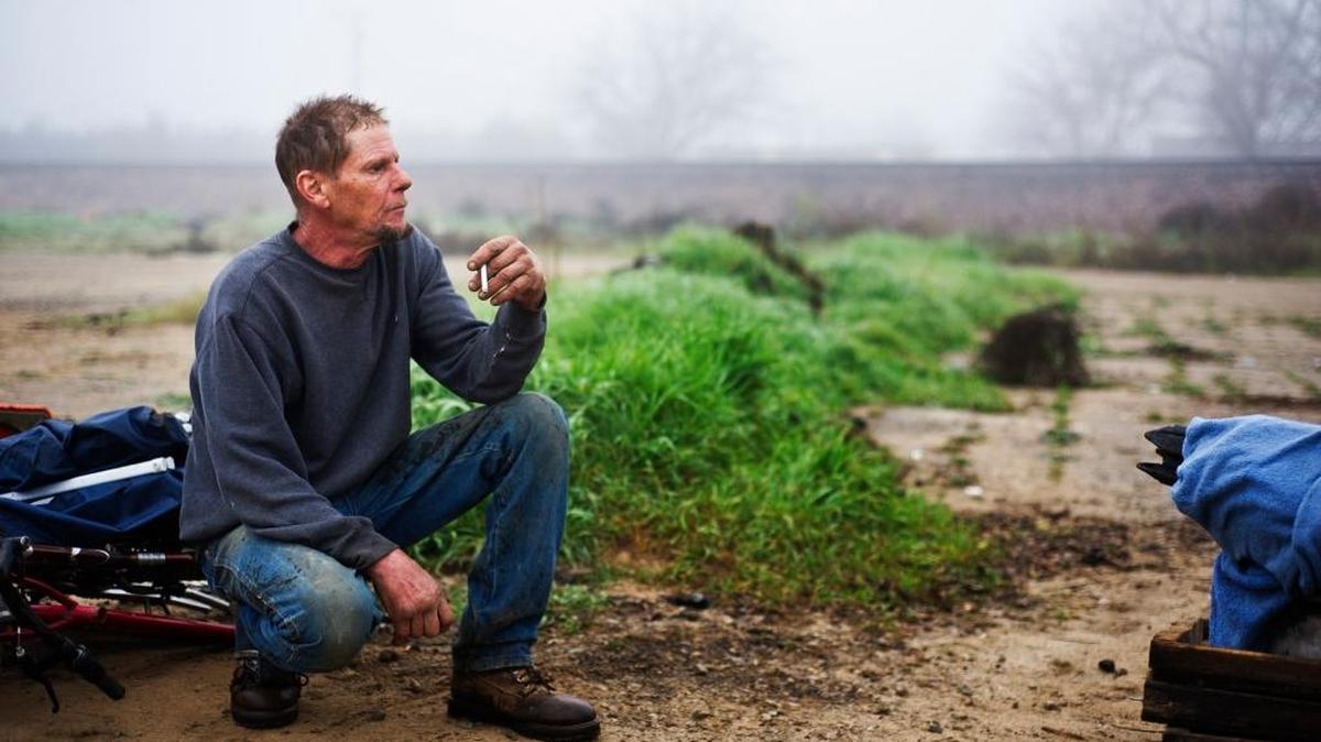 Steve Mentz, 51, looks on as California Department of Transportation employees and the California Highway Patrol work to remove a homeless encampment near the Bradley Overpass and Highway 140 at Kelly Avenue in Merced in January.