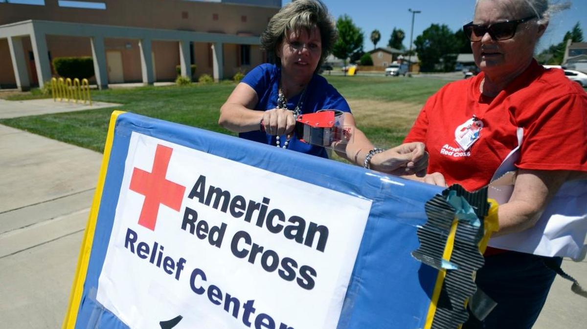 Molly Thacker of the Red Cross, right, and Michelle Roe of Merced County Human Services prepare a sign.