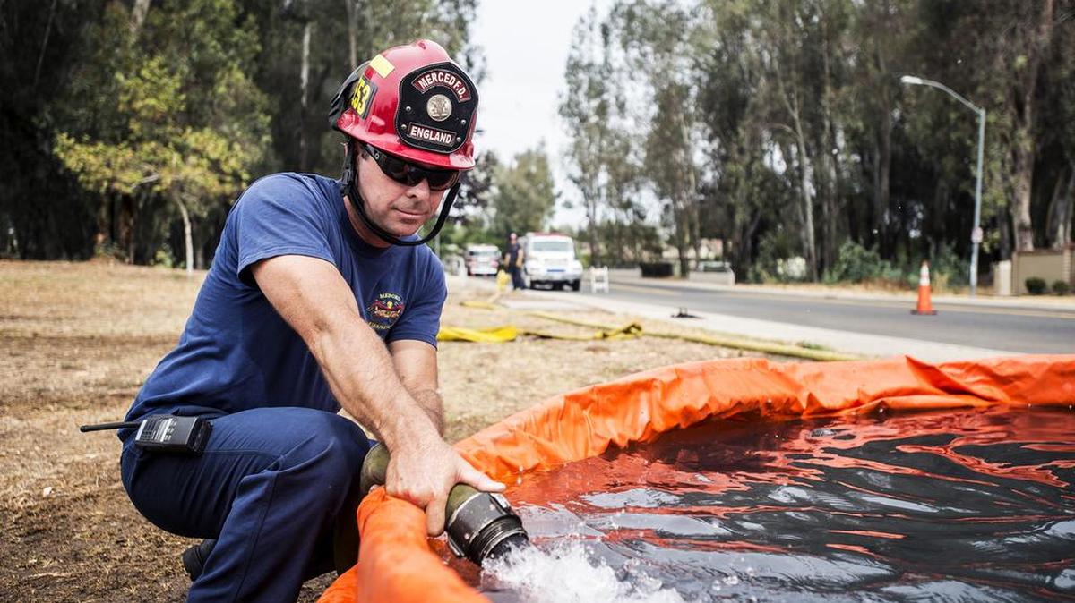 
Merced Fire Department Captain Tom England adds water to a 3,000 gallon capacity tank which is used when a reliable water source is not available, as Merced Fire Department and California Department of Forestry and Fire Protection, Merced County firefighters complete water source training exercises at Fahrens Park in Merced, Calif., Thursday, Aug. 6, 2015. In an effort to reduce water waste during training, firefighters sprayed the water onto dry areas of grass and trees throughout the park.
