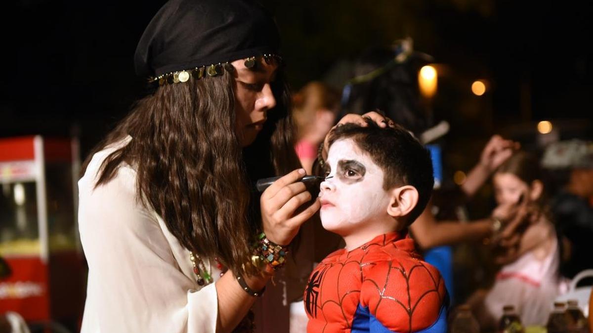 Gustine High School student Yasmine Rodriguez paints a skeleton face for 3-year-old Emiliano Hernandez on Halloween night in downtown Gustine.