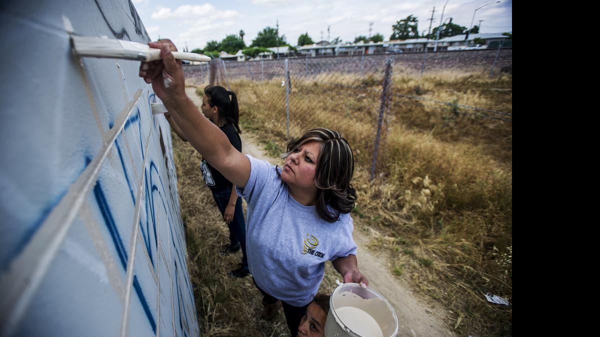 Veronica Rodriguez, 30, of Winton paints over graffiti covering a wall off Bridget Court on Friday. Once a week, a group of Winton residents volunteers its time to paint over graffiti in the community. “We try to keep it away from our children,” said Rodriguez, a mother of three.