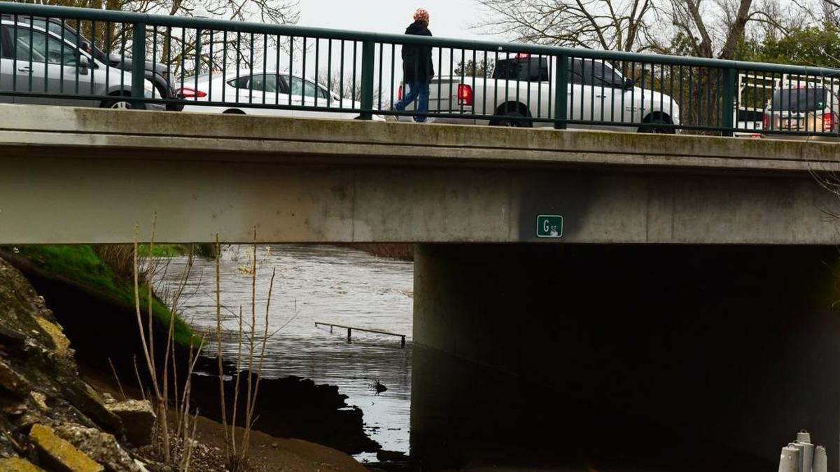 A woman uses the overpass on G Street where the bike path is flooded along Bear Creek in December.