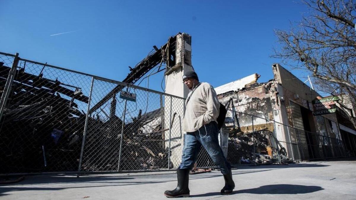 A pedestrian walks past the remains of an Asian Market destroyed by a fire in the 600 block of West Main Street in Merced, Calif., on Thursday, March 9, 2017. The market burned to the ground on Dec. 18, 2016.