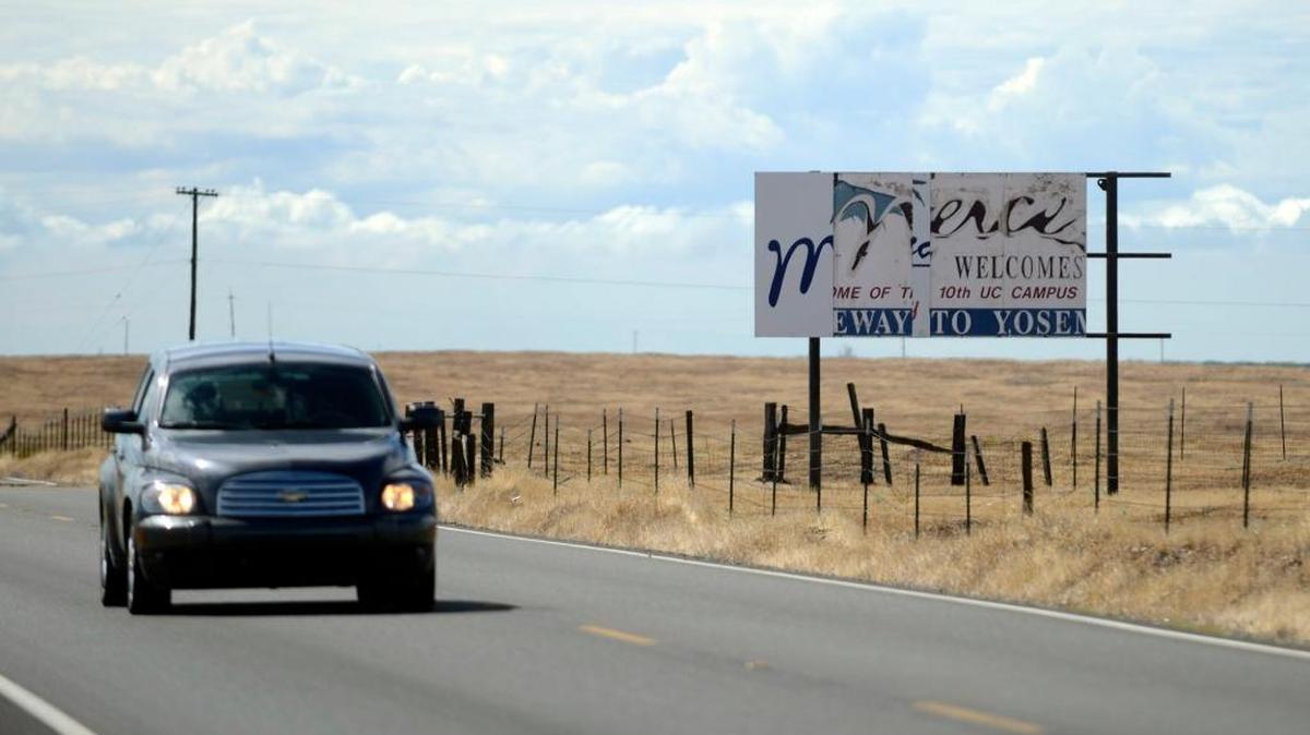A driver passes a beat-up welcome sign on Highway 140 on Thursday, Oct. 1, 2015.