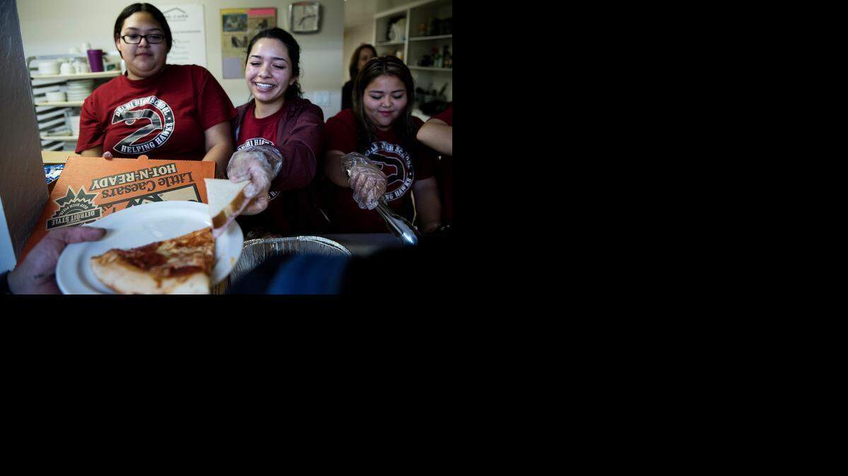 
Sophomore Anahi Mendoza, left, and senior Breanna Alamilla, middle, of the Helping Hawks, a community service club from Delhi High School, serve dinner for homeless men at the We Care Shelter in Turlock with other members of their club on Wednesday.
