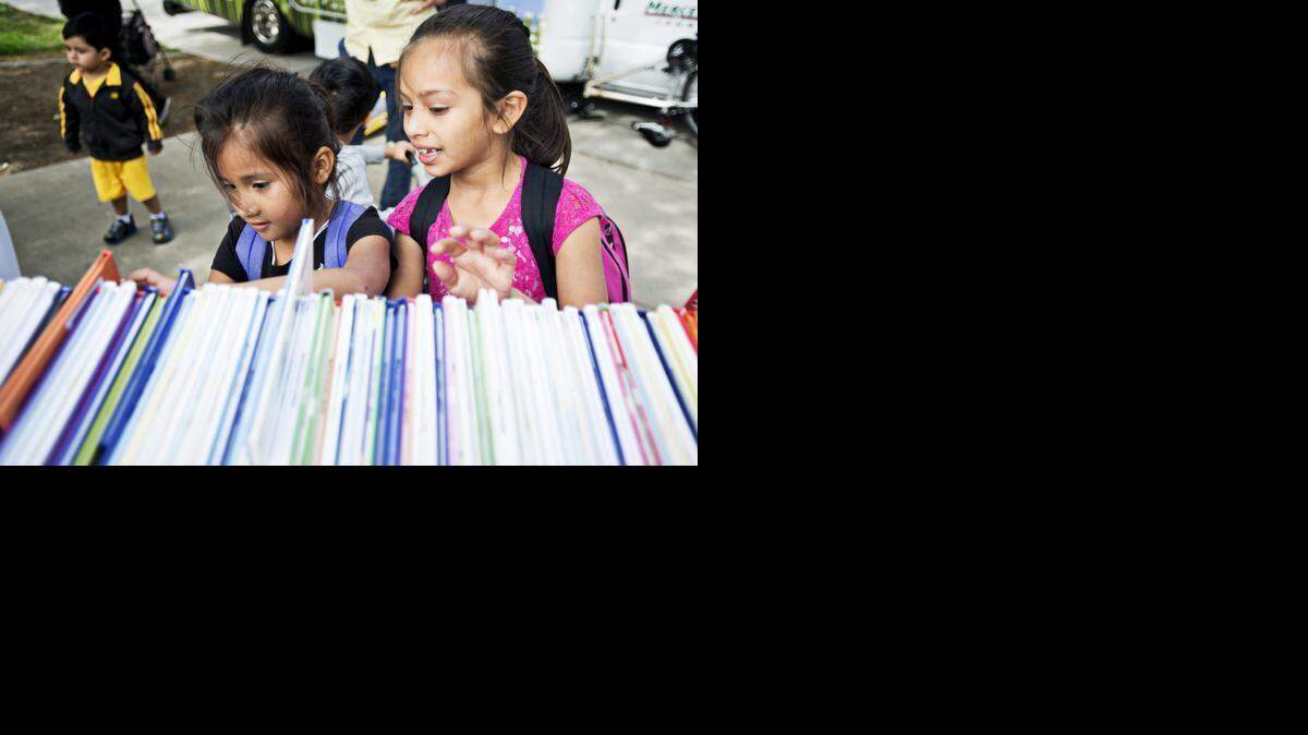 
Jazmin Martinez, 6, left, and Arivel Cervantes, 8, both of Merced, peruse a cart of books as the Merced County Library Bookmobile makes its first stop at Stephen Leonard Park in Merced on Tuesday. 
