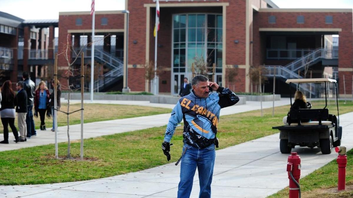 School officials gather at the front of El Capitan High School in Merced after the school was evacuated due to a bomb threat Thursday, Dec. 3, 2015.