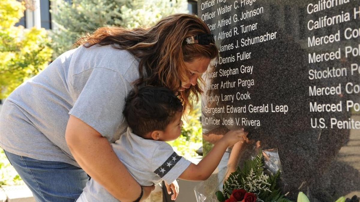 
Terry Rivera, fallen Atwater correctional Officer Jose Rivera’s mom, holds on to her grandson and Jose’s nephew Matthew Contreras, 3, as he touches the memorial stone for fallen officers where his uncle’s name is engraved, during the Merced County Peace Officer Memorial Service in 2012.
