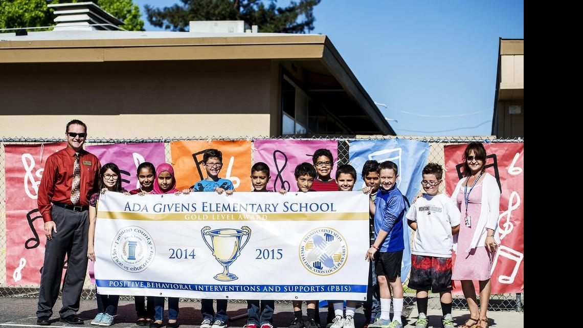 
Ada Givens Elementary School principal Dalinda Saich, right, and Doug Collins, director of pupil services, left, unveil a Model School Gold Level status banner by the Fresno County Office of Education on Tuesday for the school’s implementation of the Positive Behavior Interventions and Supports system.
