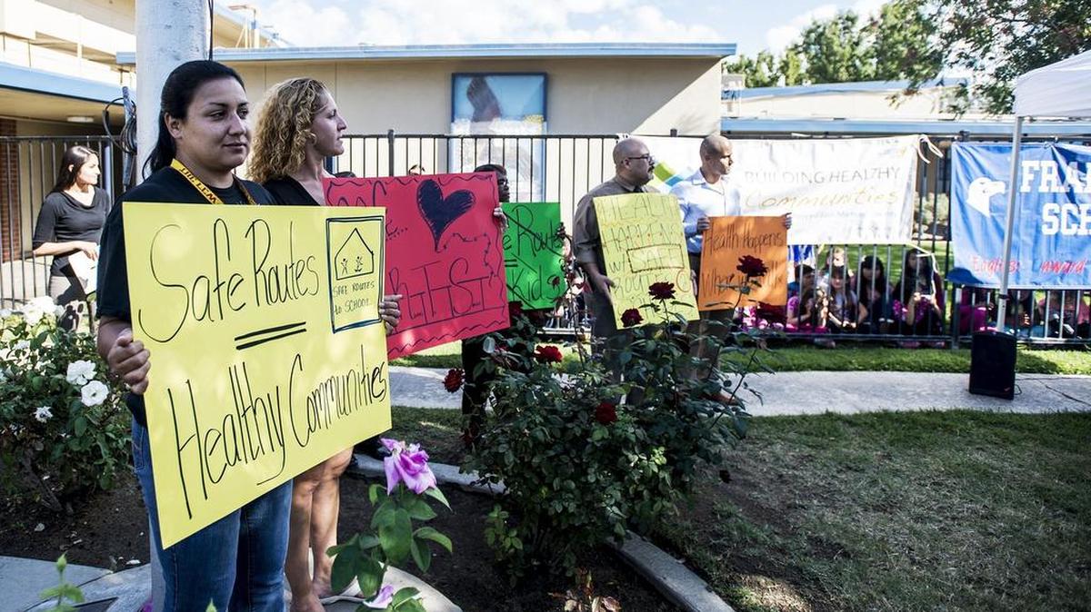 Supporters hold signs in favor of safe routes to school during a news conference announcing a $973,000 grant to improve sidewalks and streets around Franklin Elementary School in Merced on Wednesday, Oct. 28, 2015. The money will be used to add sidewalks, curbs and gutters to Lobo Avenue, a street frequently used by children walking to and from school.