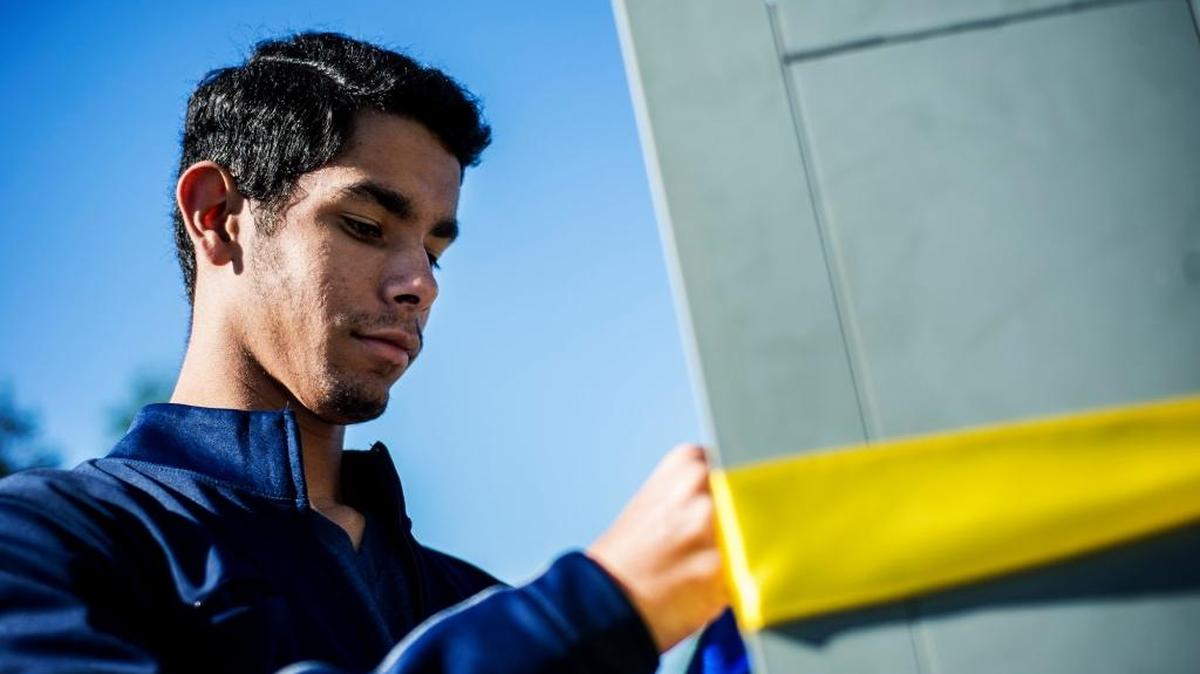 UC Merced freshman Chris Sanchez, 18, of San Diego ties blue and gold ribbons around lights on the Scholars Lane bridge on campus in November.