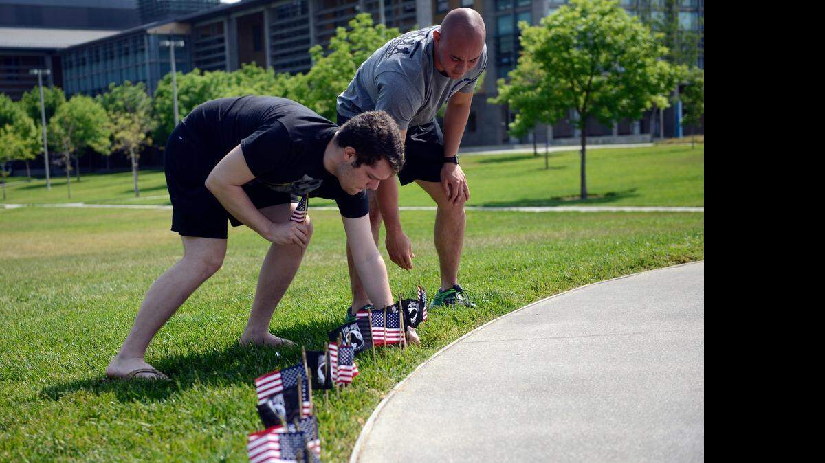 
Sean Hodgdon, 21, left, and Sergei Herbert, 22, both juniors at UC Merced, plant mini-American and POW-MIA flags around UC Merced’s “Beginnings” statue on Wednesday. The UC Merced Veterans Club asked students to help it plant about 400 flags in an early observance of Memorial Day, which happens after the university breaks for the summer.
